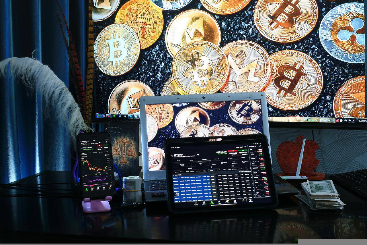 A display showcasing a cryptocurrency trading station complete with various coin symbols and laptops in use.